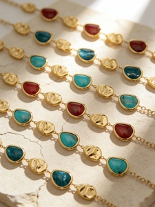 Detailed macro view of bohemian 18k gold plated chain with colorful resin teardrop charms