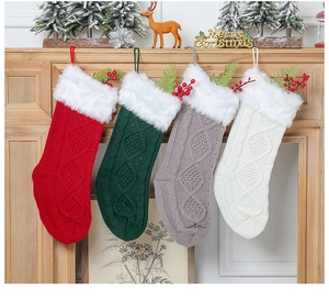 Détail de quatre chaussettes de Noël en tricot rouge, vert, gris et blanc avec fourrure