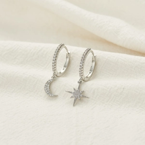 Macro shot of silver crescent moon and star hoop earrings with clear zircon stones