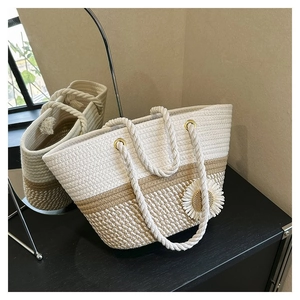 Detail of woven floral tote bag in beige and khaki with white rope handles and daisy charm