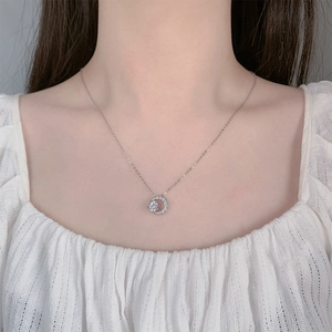 Close-up of a silver crescent moon and star pendant necklace on a female model