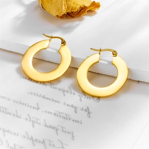 Minimalist gold geometric hoop earrings on a decorative stone and dry flower setting