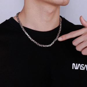 Close-up of a silver stainless steel square weave chain necklace worn by a male model