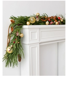 Close-up of Norfolk pine garland with red ornaments, gold stars and warm LED lights