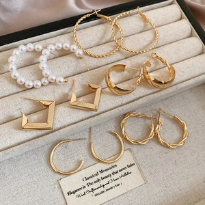 Detail of diverse gold hoop earrings set with pearls and geometric shapes in velvet box