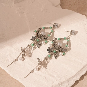 Detail of vintage silver earrings with butterfly charms, faux pearls and floral elements
