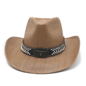 Detail of western straw hat with black leather band and vintage bronze bull head badge