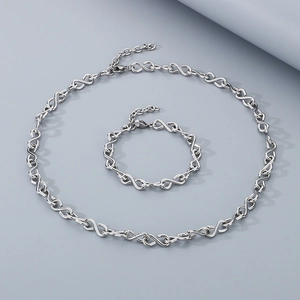 Detail of silver infinity symbol links on stainless steel necklace and bracelet set