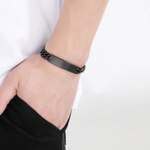 Macro shot of a black stainless steel ID bracelet with matte plate on a male wrist