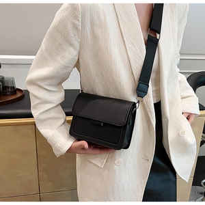 Side view of model wearing a black matte leather square crossbody bag with wide strap