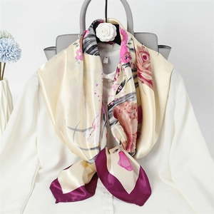 Detailed view of floral silk scarf in beige with purple border draped on a white shirt