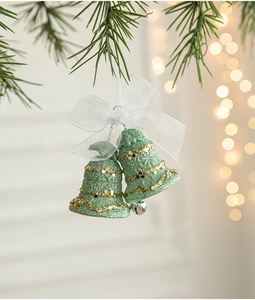 Detailed close-up of green glitter Christmas bells with gold sequins and a white bow
