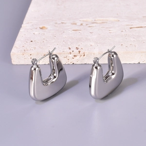 Close-up of polished silver stainless steel chunky U-shaped hoop earrings on stone