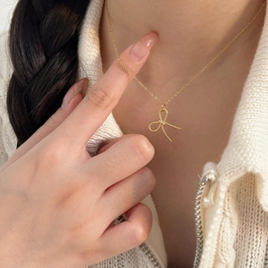 Elegant gold bow pendant necklace in 925 sterling silver worn by a model on white knitwear