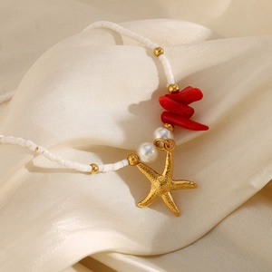 Detail of 18K gold starfish pendant with red coral stones and pearls on beaded chain