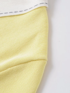 Detail of yellow pique knit fabric texture with decorative navy blue stitching accents