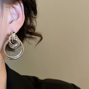 Détail de boucles d'oreilles créoles argentées multicouches portées par un mannequin