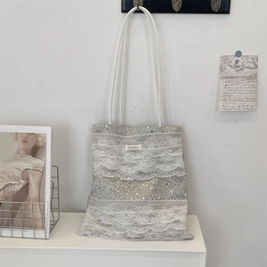 Detailed close-up of cream lace tote bag with silver sequins and bead decorations