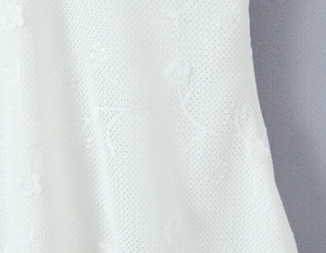 Close-up of white mesh fabric featuring delicate floral embroidery and lace texture