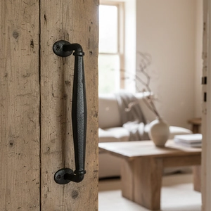 Detail of vintage cast iron door handle with hammered texture on a rustic wooden pillar