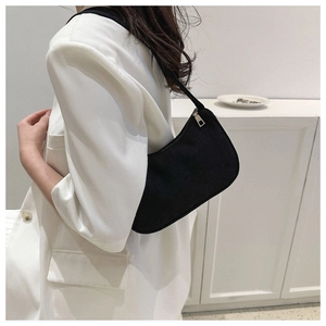 Detailed view of black corduroy shoulder bag with silver zipper on model's shoulder