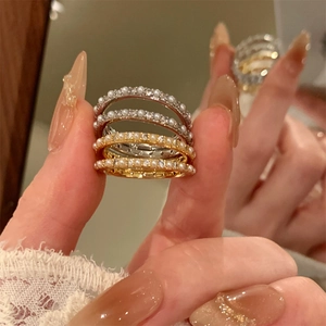 Detail of 14K gold plated stacked rings with pearls and zircons on fingers