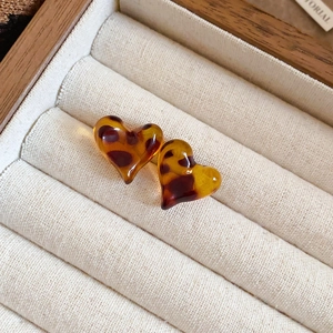Macro shot of amber leopard print heart earrings in a beige velvet jewelry box