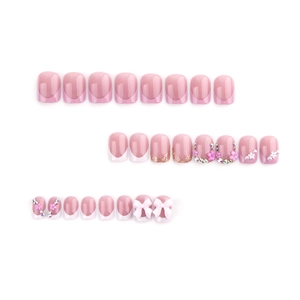 Pink and white press-on nails with rhinestone flowers and gold glitter accents