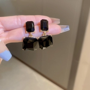 Macro detail of geometric black crystal earrings with elegant gold claw settings