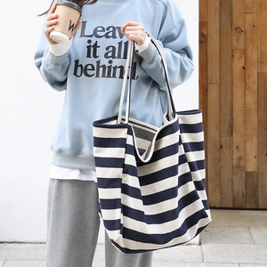 Striped navy and white canvas tote bag for women in a casual urban street style setting