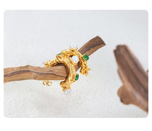 Détail de boucles d'oreilles vintage dorées avec cristaux vert émeraude et perles