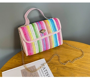 Detail of colorful woven handbag with crocodile texture and gold metal turn-lock closure