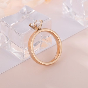 Detail of four-prong solitaire zircon ring in rose gold finish on minimalist background