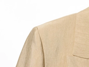Detailopname van de schoudernaad van een satijnen blazer in champagnegoud van kwaliteit