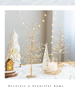 Golden beaded Christmas tree decoration set on a snowy tabletop with warm lighting