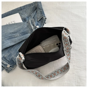 Large black nylon crossbody bag interior showing spacious capacity with wide geometric strap