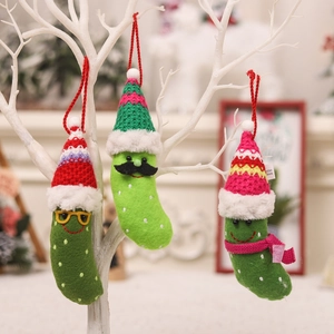 Three green knitted pickle Christmas ornaments with glasses and scarves hanging on white branches