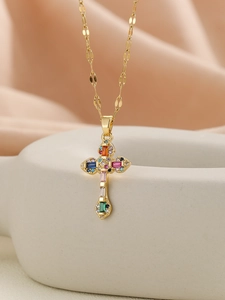 Detailed macro view of gold cross necklace with multi-colored cubic zirconia stones