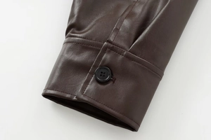 Detailed close-up of dark brown faux leather jacket cuff with black button and stitching
