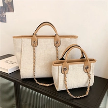 Close-up of canvas tote bag set featuring leather handles and chic woven chain detail