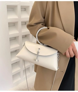 Detail of a chic cream handbag with diamond ring handle and silver metal chain strap