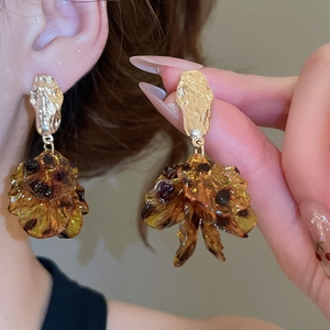 Detailed view of amber resin petal tassels and hammered gold studs worn by a model