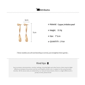 Vue détaillée de longues boucles d'oreilles dorées torsadées avec perles de 7x1cm