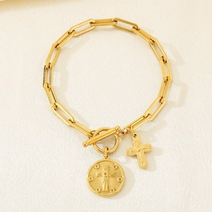 Macro shot of gold paperclip chain bracelet with OT toggle clasp and cross charms