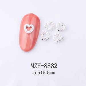 Close-up of 5.5mm silver heart nail charms with white pearls on pink nails