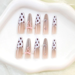 Faux ongles longs avec motif léopard, nœuds roses et strass brillants sur support blanc
