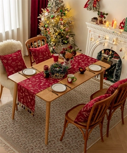 Close-up of red Christmas table runner featuring snowflake and deer motifs with fringe detail