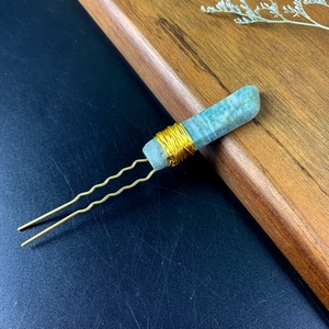 Detail of green natural crystal hair pin with golden wire wrap and wavy fork design