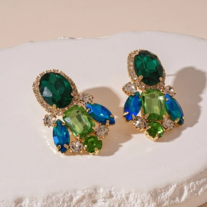 Macro detail of Bohemian gold earrings featuring green oval stones and blue marquise crystals