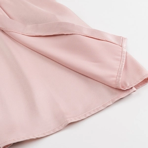 Close-up of pink pleated dress hemline showing premium silk-like fabric and fine stitching
